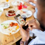 hands with smartphone picturing food at restaurant
