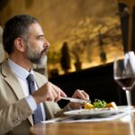 Handsome senior man eating lunch in restaurant